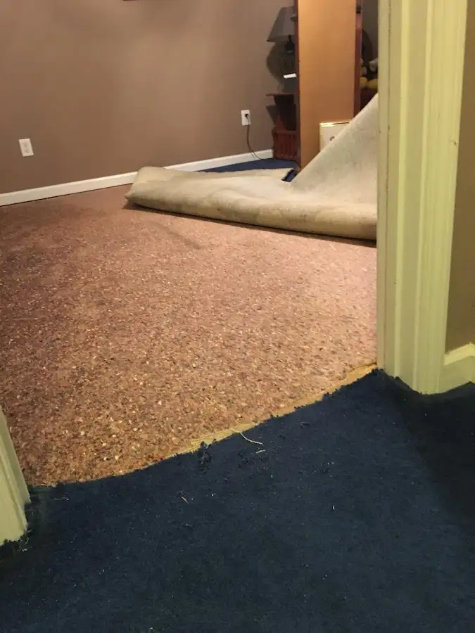 Carpet pad removal revealing water damage during Water Mitigation Services in Parsons